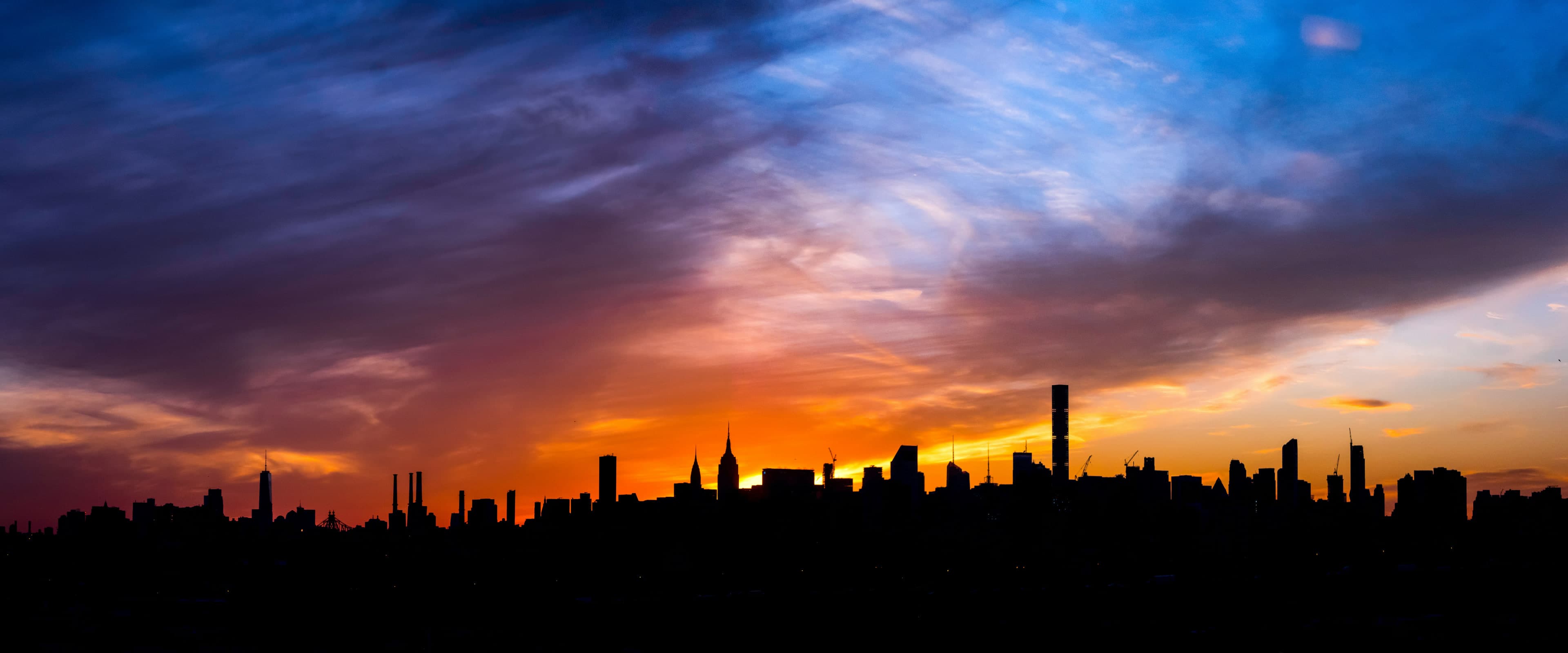 The Manhattan skyline in silhouette against a sunset sky